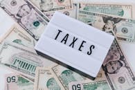 pexels-photo-4386367-4386367 US dollar bills surrounding a sign showing 'TAXES'. Ideal for financial context.